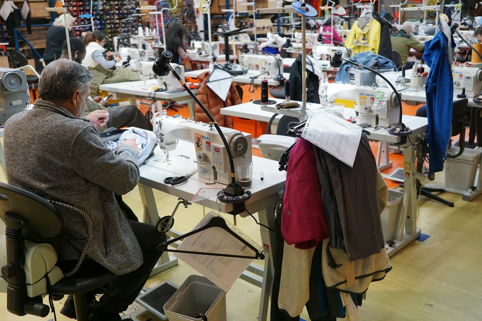Costureiro trabalhando em máquina numa oficina de costura